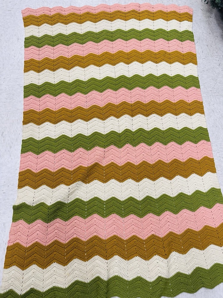 Handmade crochet chevron blanket with pink, mustard, white, and green stripes.