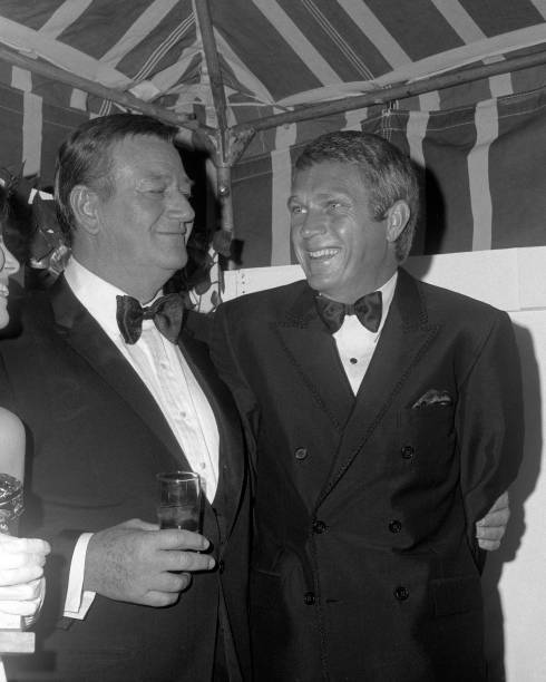 John Wayne and Steve McQueen share a laugh during the 24th Annual - Old Photo 2