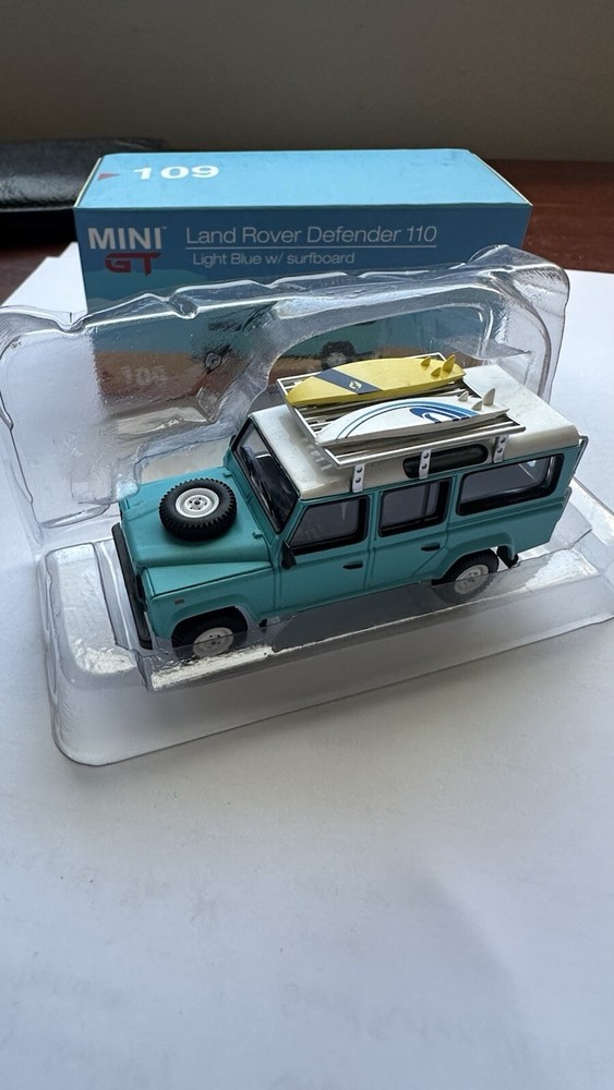 MINI GT 109 Land Rover Defender 110 Light Blue w/ Surfboard RHD MINIGT