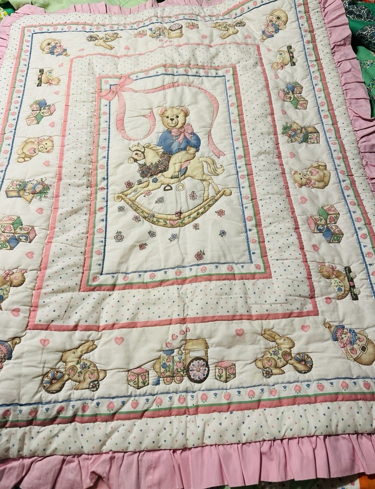 A vintage baby quilt featuring teddy bears, bunnies, and toys.