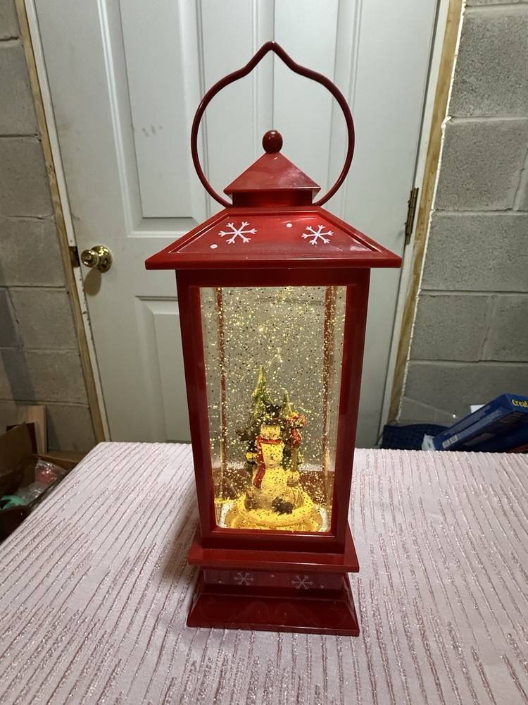 Christmas snow globe lantern featuring a snowman in a red lantern frame.