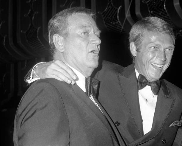 John Wayne and Steve McQueen share a laugh during the 24th Annual - Old Photo