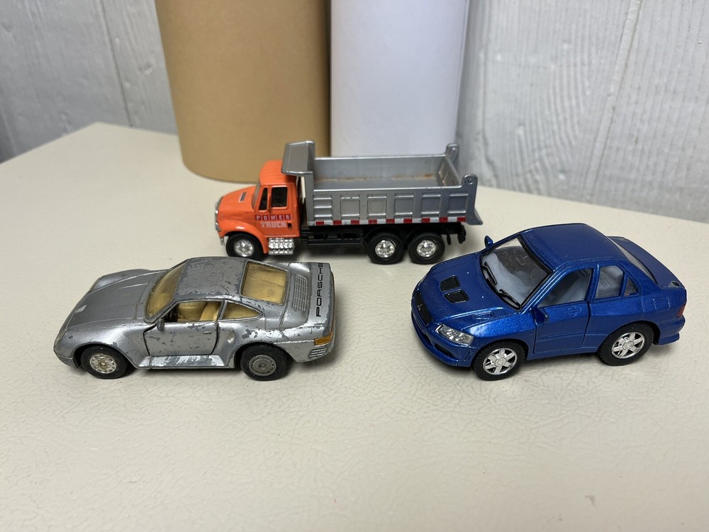 Lot Of Three Diecast Vehicles, One Dump Truck And Two Cars. 12/6/24 M